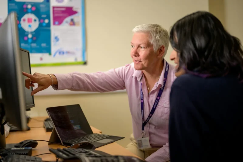 IT support specialist helping a colleague at a computer