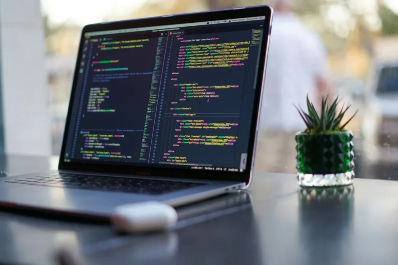 Laptop showing website code on a desk